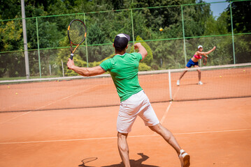 Young athletic couple playing tennis on the court.