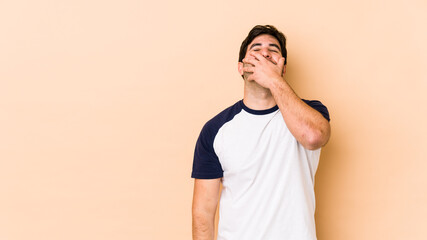 Young man isolated on beige background laughing happy, carefree, natural emotion.