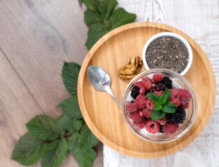Chia pudding with berries and walnuts on the bamboo plate. Top view