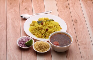 Aloo/Kanda Poha or Tarri Pohe with spicy chana masala/curry. Served in ceramic plate.