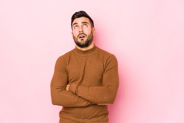 Young caucasian man against a pink background isolated tired of a repetitive task.