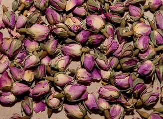A lot of tea from dried buds and petals of a lilac damask rose lies on a paper background