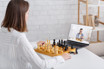 Online chess at home. Woman and guy play on board games using laptop
