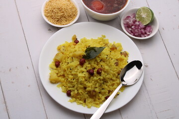 Aloo/Kanda Poha or Tarri Pohe with spicy chana masala/curry. Served in ceramic plate.
