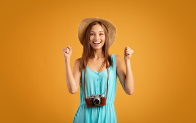 Emotional woman tourist with camera raising fists up
