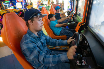 Fototapeta na wymiar Teenagers boy plays on the gaming car simulator in the club.