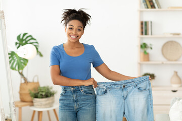 Happy Slim Black Woman Showing Old Jeans Standing At Home