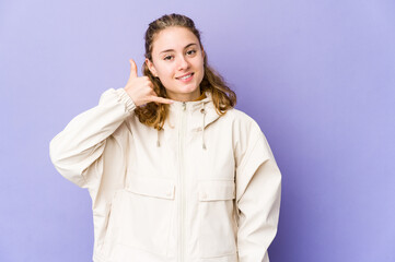 Young caucasian woman on purple background showing a mobile phone call gesture with fingers.