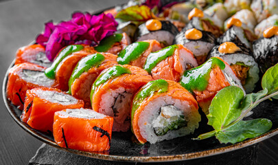 set of sushi roll with salmon, avocado, cream cheese, cucumber, rice, caviar, eel, tuna in plate on black wooden table background