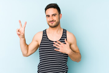 Fototapeta premium Young caucasian man isolated on blue background taking an oath, putting hand on chest.