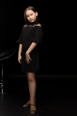 Cute little girl in a beautiful dress on a black background.