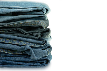 Stack of various shades of blue jeans trousers at white background
