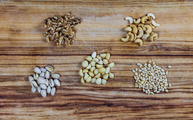 piles of cashew, walnuts, pine nuts, macadamia, pistachio on wooden background