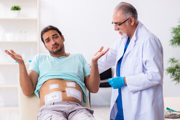 Injured young man visiting experienced male doctor