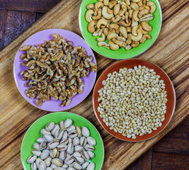 different coloured plates with different nuts on wooden background