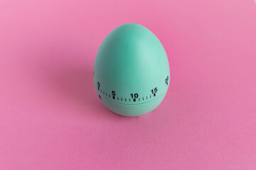green egg timer on pink background. Happy Easter in the kitchen. Home related, home staying. Free copy space. Flat lay, top view