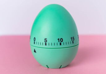 green egg timer on pink background. Happy Easter in the kitchen. Home related, home staying. Free copy space. Flat lay, top view