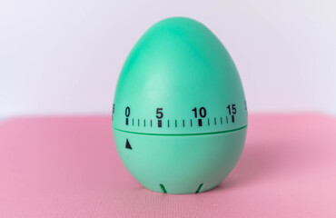 green egg timer on pink background. Happy Easter in the kitchen. Home related, home staying. Free copy space. Flat lay, top view