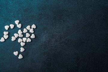 White medical pills in the form of hearts on a blue background.