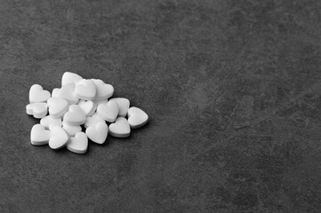 White medical pills in the form of hearts on a gray background.