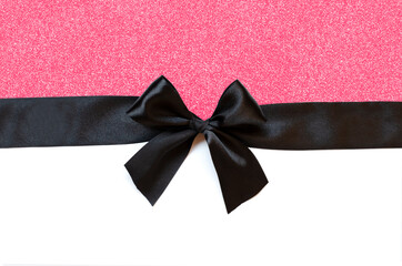 Black ribbon with bow isolated on white and pink background.