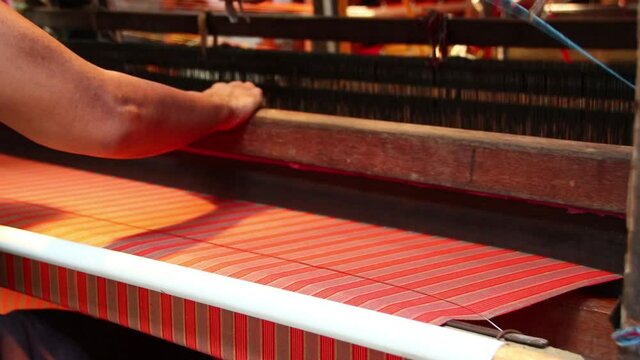 workers weaving thread into cloth using traditional looms, low light video in a dark room, Pekalongan