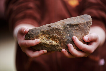 Close-up of children's hands holding a large stone