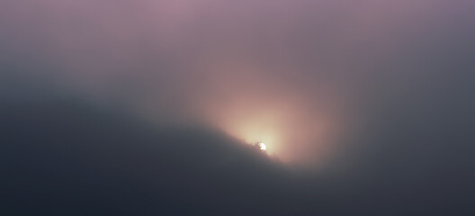 Detail of sun going up at sunrise through trees and misty fog. Toned photo, Czech landscape