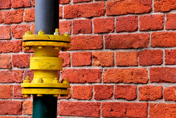 Yellow water pipe and red brick wall as city background.