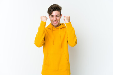 Young caucasian man isolated on white background cheering carefree and excited. Victory concept.