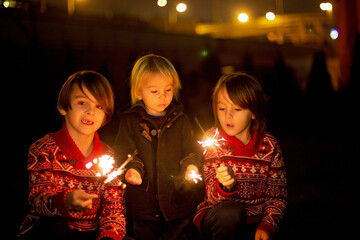 Obraz na płótnie Canvas Waist up portrait of happy children celebrating New Year together and lighting sparklers