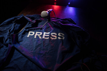 Freedom of the press and journalism concept. Blue journalist (press) vest in dark with backlight and fog. Selective focus