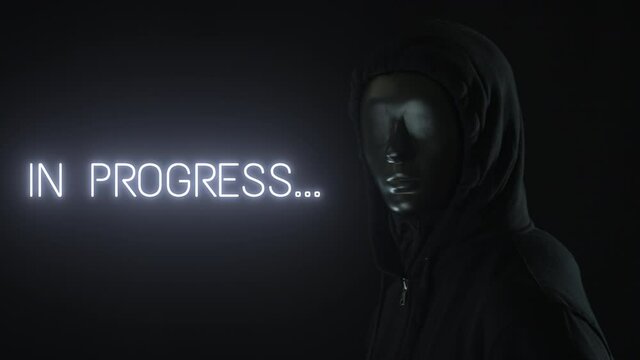 Man wearing black mask and the light revealing IN PROGRESS text
