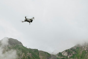 Fototapeta na wymiar Flying photography drone in the cloudy sky in the mountains, moody weather, natural colors
