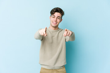Naklejka premium Young caucasian man isolated on blue background cheerful smiles pointing to front.