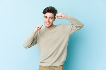 Young caucasian man isolated on blue background celebrating a special day, jumps and raise arms with energy.