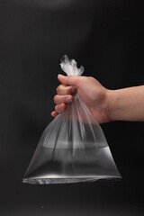 One hand is picking up a plastic bag full of water