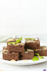 Squares Chocolate brownie with almond sliced set on white cafe table.