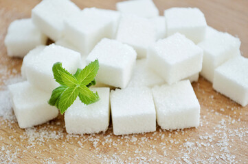 Refined sugar and fresh mint leaves on wooden background.