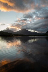 Fototapeta na wymiar Beautiful sunrise landscape image looking across Loweswater in the Lake District towards Low Fell and Grasmere with vibrant sunrise sky breaking on the mountain peaks