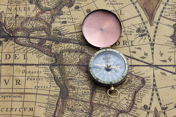 Classic round compass on background of old vintage map of world as symbol of tourism with map and compass, travel with with map and compass and outdoor activities with with map and compass