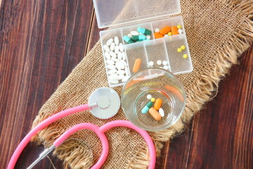 stethoscope with drugs in glass and personal medicine in container