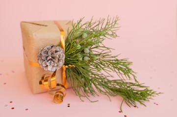 christmas gift in kraft paper with fir branch and lollipop on pink background with multicolored candy with place for text christmas concept