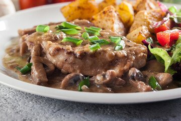 Pork loin chop with mushroom sauce and baked potatoes
