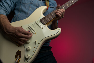 Man playing white electric guitar on a jean jacket