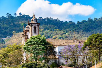 One of the many historic churches in baroque and colonial style from the 18th century amid the hills and vegetation of the city Ouro Preto in Minas Gerais, Brazil