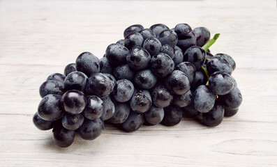Fresh black grapes on white wooden boards.