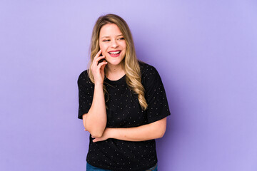 Young caucasian woman isolated on purple background laughs happily and has fun keeping hands on stomach.