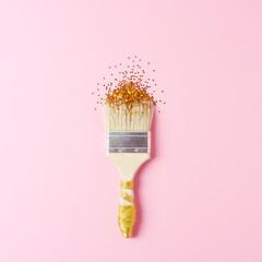 Paint brush with golgen confetti on pink background. Christmas, winter, new year concept. Flat lay,...