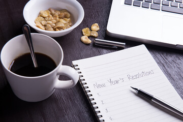 Conceptual,Top view office desk mockup: laptop, notebook, smartphone, snack bean, and cup of coffee on rustic brown wooden desk. New year 2017 resolution